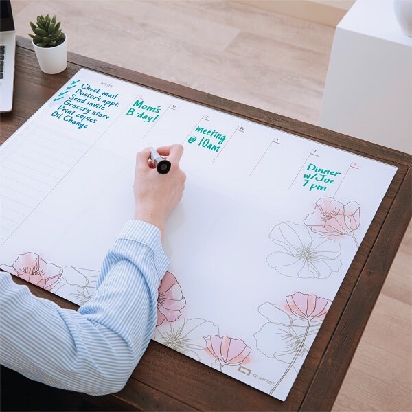 Person writing on Quartet Desktop Glass Floral Weekly Planner